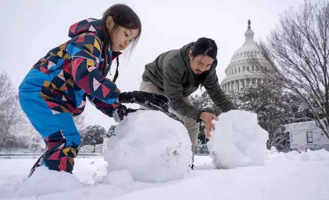Johnny Hong, of Washington, and his daughter Eliyah Hong, 5, build a snowman by the Capitol, Wednesday, Feb. 12, 2025, after a snowstorm in Washington. (AP Photo/Jacquelyn Martin)