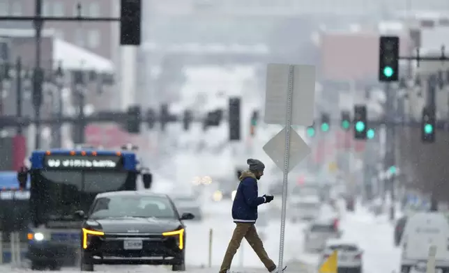 A pedestrian crosses a snowy street in downtown Kansas City, Mo., as a winter storm passed through the area Wednesday, Feb. 12, 2025. (AP Photo/Charlie Riedel)