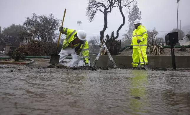 Crews work in the rain in the Eaton Fire zone during a storm Thursday, Feb. 13, 2025, in Altadena, Calif. (AP Photo/Etienne Laurent)