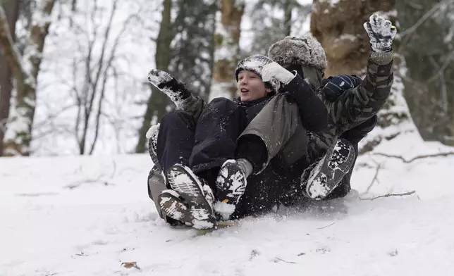 From left, Elijah, Jackson and Malian ride on a sled together down a hill at Laurelhurst Park on Thursday, Feb. 13, 2025, in Portland, Ore. (AP Photo/Jenny Kane)