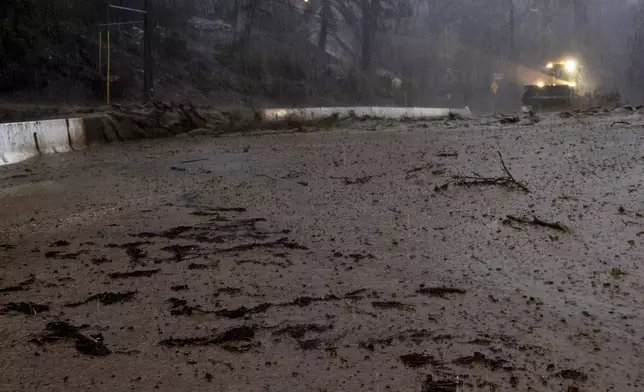 Mud is cleared from a road in the Eaton Fire zone during a storm Thursday, Feb. 13, 2025, in Altadena, Calif. (AP Photo/Etienne Laurent)