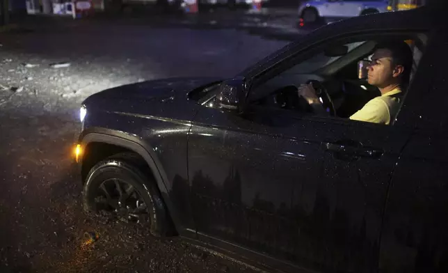 A motorist drives through a mud-covered road in the Palisades Fire zone during a storm Thursday, Feb. 13, 2025, in the Pacific Palisades neighborhood of Los Angeles. (AP Photo/Ethan Swope)