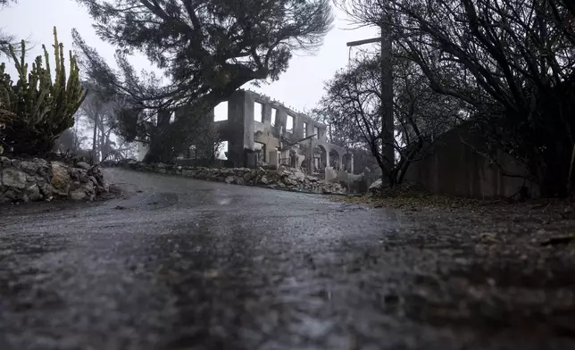 A fire-damaged property is seen in the Eaton Fire zone during a storm Thursday, Feb. 13, 2025, in Altadena, Calif. (AP Photo/Etienne Laurent)