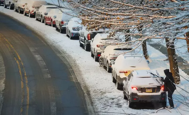 A driver removes snow from a car before pulling away from parking spot after overnight snow fall covered street and vehicles in Philadelphia, Wednesday, Feb. 12, 2025. (Alejandro A. Alvarez/The Philadelphia Inquirer via AP)