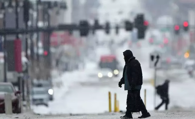 Pedestrians cross a snowy street in downtown Kansas City, Mo., as a winter storm passed through the area Wednesday, Feb. 12, 2025. (AP Photo/Charlie Riedel)