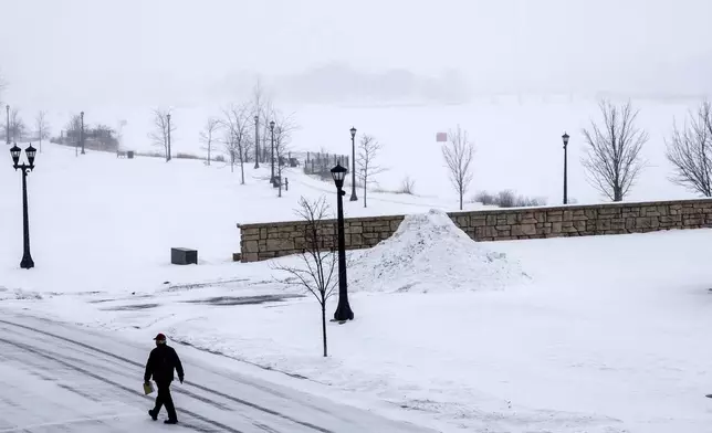A person walks across the street as a snowstorm rolls in, Wednesday, Feb. 12, 2025 in Uptown Bay City, Mich. (Kaytie Boomer/The Bay City Times via AP)