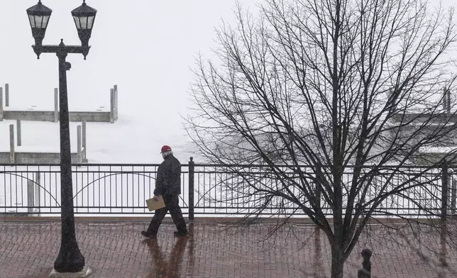 A person walks down the sidewalk as a snowstorm rolls in, Wednesday, Feb. 12, 2025 in Uptown Bay City, Mich. (Kaytie Boomer/The Bay City Times via AP)