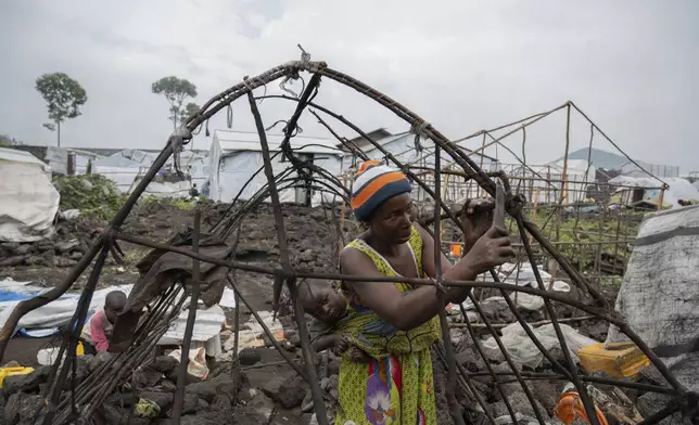 A woman and her child who were displaced by the fighting between M23 rebels and government soldiers prepare to leave the camp following an instruction by M23 rebels in Goma, Democratic Republic of the Congo, Tuesday, Feb. 11, 2025. (AP Photo/Moses Sawasawa)