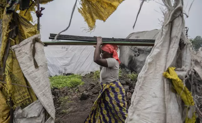 A woman displaced by the fighting between M23 rebels and government soldiers leaves the camp following an instruction by M23 rebels in Goma, Democratic Republic of the Congo, Tuesday, Feb. 11, 2025. (AP Photo/Moses Sawasawa)