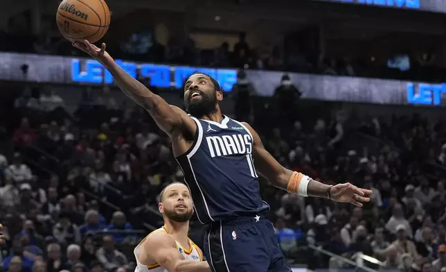 Dallas Mavericks guard Kyrie Irving (11) scores against Golden State Warriors guard Stephen Curry during the second half of an NBA basketball game in Dallas, Wednesday, Feb. 12, 2025. (AP Photo/LM Otero)