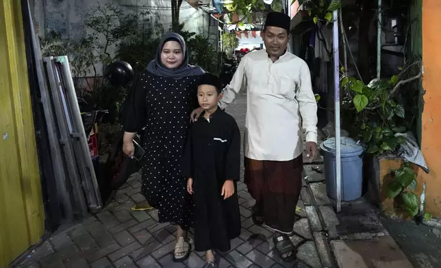 Samsul Anwar, right, his wife Rekanita Amelia and nephew Argha Al Khawarizmi prepare for a torch parade ahead of the holy fasting month of Ramadan, in Tangerang, Indonesia, Thursday, Feb. 27, 2025. (AP Photo/Tatan Syuflana)