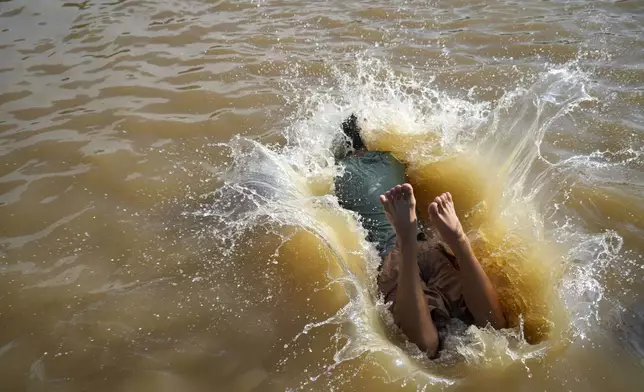 A man jumps into the Cisadane River, ahead the holy fasting month of Ramadan in Tangerang, Indonesia, Friday, Feb 28, 2025. (AP Photo/Tatan Syuflana)