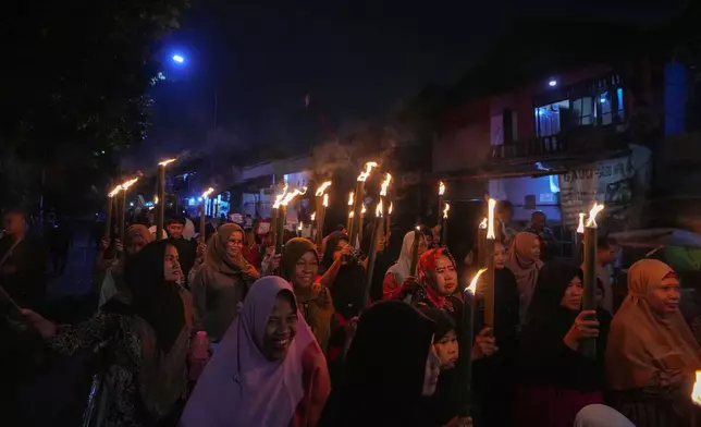 Muslim women hold torches during a parade ahead of the holy fasting month of Ramadan, in Tangerang, Indonesia, Thursday, Feb. 27, 2025. (AP Photo/Tatan Syuflana)