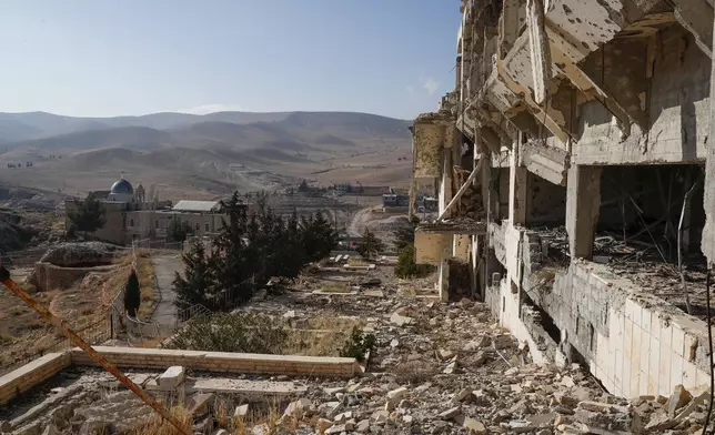 The remains of the Safir Hotel, destroyed in clashes between al-Qaida-linked fighters and Syrian government forces over a decade ago, overlook the Church of Saints Sergius and Bacchus in the town of Maaloula, Syria, Sunday, Jan. 12, 2025. (AP Photo/Omar Sanadiki)