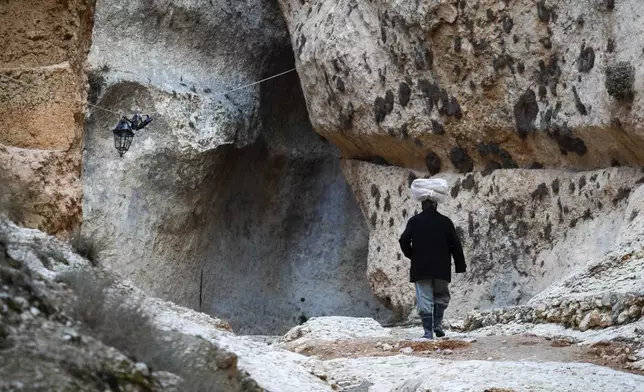 A man carrying loaves of bread on his head walks through a historic canyon in the town of Maaloula, Syria, Sunday Jan. 12, 2025.AP Photo/Omar Sanadiki)