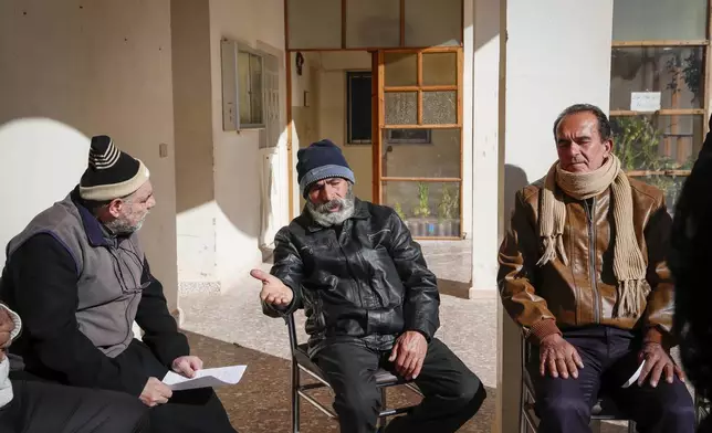Father Jalal Ghazal, left, listens to Christians expressing security concerns outside the Church of Saint George in the town of Maaloula, Syria, Sunday, Jan. 12, 2025. (AP Photo/Omar Sanadiki)