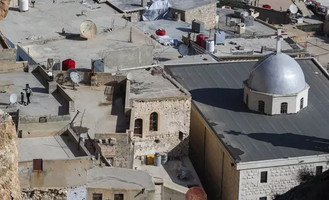 A mother walks with her son on the rooftop of a building in the town of Maaloula, Syria, Sunday Jan. 12, 2025. (AP Photo/Omar Sanadiki)