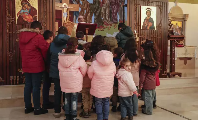Children pray with Father Jalal Ghazal during Sunday Mass at the Church of Saint George in the town of Maaloula, Syria, Sunday, Jan. 12, 2025. (AP Photo/Omar Sanadiki)