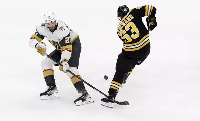 Vegas Golden Knights defenseman Shea Theodore (27) and Boston Bruins left wing Brad Marchand (63) battle for the puck during the second period of an NHL hockey game, Saturday, Feb. 8, 2025, in Boston. (AP Photo/Mark Stockwell)