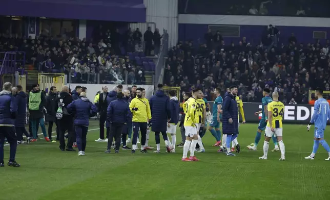 Players leave the pitch after an incident with supporters during the Europa League playoff second leg soccer match between Anderlecht and Fenerbahce at the RSC Anderlecht stadium in Brussels, Thursday, Feb. 20, 2025. (AP Photo/Omar Havana)