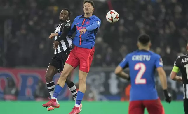 PAOK's Baba Rahman, left, jumps for a header with FCSB's David Miculescu during the Europa League playoff stage second leg soccer match between FCSB and PAOK at the National Arena stadium, Thursday, Feb. 20, 2025. (AP Photo/Andreea Alexandru)
