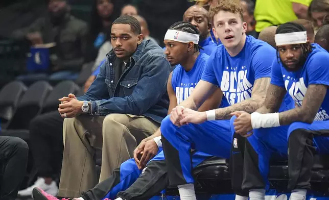 Dallas Mavericks forward P.J. Washington, left, sits on the bench in street clothes during the first half of an NBA basketball game against the Miami Heat Thursday, Feb. 13, 2025, in Dallas. (AP Photo/Julio Cortez)