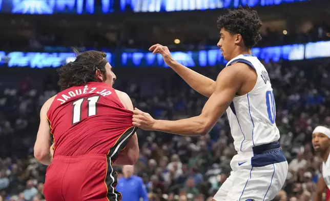 Dallas Mavericks guard Max Christie, right, grabs at the jersey of Miami Heat guard Jaime Jaquez Jr. as he drives to the basket during the first half of an NBA basketball game Thursday, Feb. 13, 2025, in Dallas. (AP Photo/Julio Cortez)