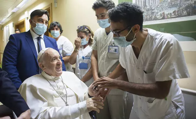 FILE - Pope Francis is greeted by hospital staff as he sits in a wheelchair inside the Agostino Gemelli Polyclinic in Rome, Sunday, July 11, 2021, where he was hospitalized for intestine surgery. (Vatican Media via AP, file)