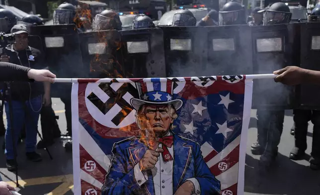 Protesters burn posters depicting President Donald Trump during a rally against U.S. Secretary of State Marco Rubio's visit in Panama City, Sunday, Feb. 2, 2025. (AP Photo/Matias Delacroix)