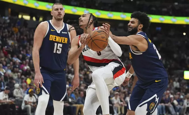 Portland Trail Blazers guard Dalano Banton, center, is fouled by Denver Nuggets guard Jamal Murray, right, while driving to the basket past center Nikola Jokic in the second half of an NBA basketball game Wednesday, Feb. 12, 2025, in Denver. (AP Photo/David Zalubowski)
