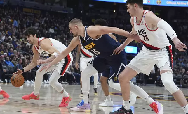 Portland Trail Blazers forward Deni Avdija, left, collects a loose ball as Denver Nuggets center Nikola Jokic (15) gets tangled up with Trail Blazers center Donovan Clingan in the second half of an NBA basketball game Wednesday, Feb. 12, 2025, in Denver. (AP Photo/David Zalubowski)