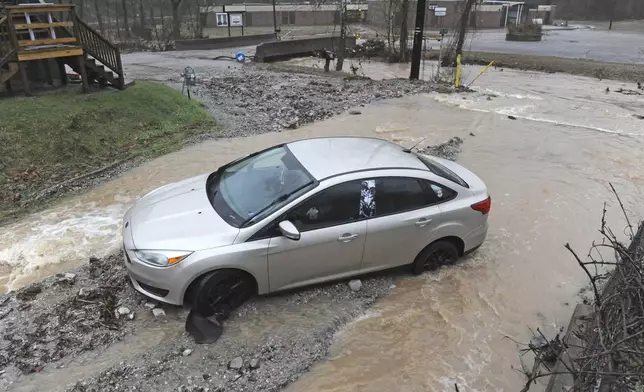 A car is stuck in debris on Bear Fork Road along Kanawha Two Mile Creek near the Edens Fork Road overpass in Kanawha County outside of Charleston, W.Va., on Thursday, Feb. 6, 2025. (Christopher Millette/Charleston Gazette-Mail via AP)