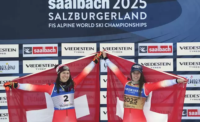 Switzerland's Camille Rast, right, winner of a gold medal in a women's slalom, celebrates on the podium with silver medalist Switzerland's Wendy Holdener, at the Alpine Ski World Championships, in Saalbach-Hinterglemm, Austria, Saturday, Feb. 15, 2025. (AP Photo/Giovanni Auletta)