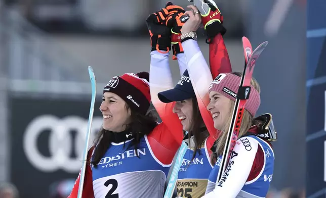 Switzerland's Camille Rast, center, winner of a gold medal in a women's slalom, celebrates on the podium with silver medalist Switzerland's Wendy Holdener, left, and bronze medalist Austria's Katharina Liensberger, at the Alpine Ski World Championships, in Saalbach-Hinterglemm, Austria, Saturday, Feb. 15, 2025. (AP Photo/Marco Trovati)