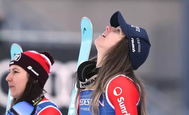 Switzerland's Camille Rast, right, winner of a gold medal in a women's slalom, looks up from the podium next to silver medalist Switzerland's Wendy Holdener, left, at the Alpine Ski World Championships, in Saalbach-Hinterglemm, Austria, Saturday, Feb. 15, 2025. (AP Photo/Marco Trovati)