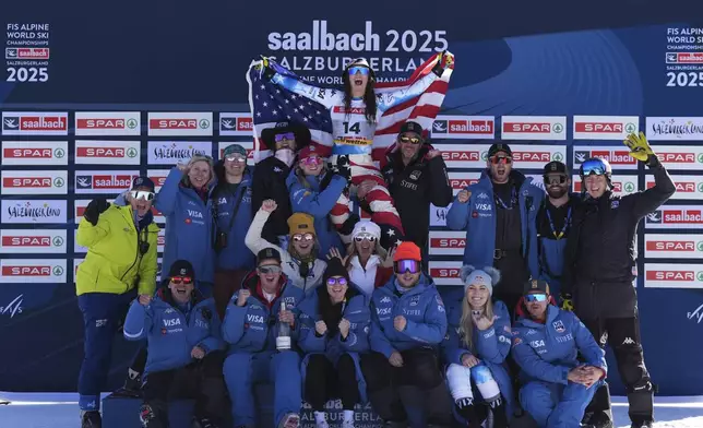 United States' Lauren Macuga, top, celebrates on the podium with the team, including United States' Lindsey Vonn, bottom right, after taking joint third place in a women's Super-G, at the Alpine Ski World Championships, in Saalbach-Hinterglemm, Austria, Thursday, Feb. 6, 2025. (AP Photo/Giovanni Auletta)