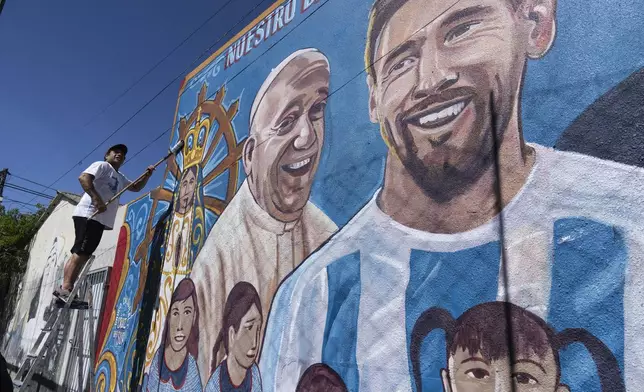 Roberto Coria preserves a mural depicting Pope Francis and soccer star Lionel Messi in Buenos Aires, Argentina, Wednesday, Feb. 19, 2025. (AP Photo/Rodrigo Abd)