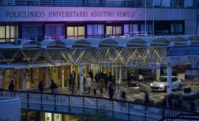 People walk in front of the main entrance of the Agostino Gemelli Polyclinic in Rome, Wednesday, Feb. 19, 2025, where the Pontiff is hospitalized since Friday, Feb. 14. (AP Photo/Andrew Medichini)