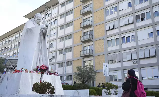 A woman prays in front of a statue of Pope John Paul II in front of the Agostino Gemelli Polyclinic, in Rome, Thursday, Feb. 20, 2025, where the Pontiff is hospitalized since Friday, Feb. 14.(AP Photo/Alessandra Tarantino)