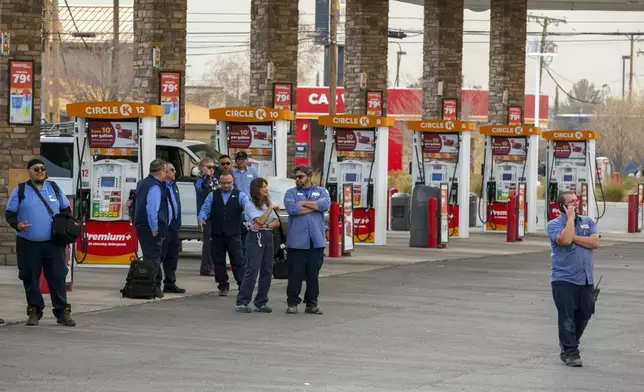 Employees of the public transportation service Sun Metro wait at a gas station after being evacuated from their operations center due to a fire Tuesday, Feb. 11, 2025, in El Paso, Texas. (AP Photo/Andres Leighton)