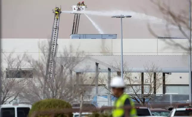Firefighters spray water on a fire at the the maintenance facilities of the public transportation service Sun Metro Tuesday, Feb. 11, 2025, in El Paso, Texas. (AP Photo/Andres Leighton)