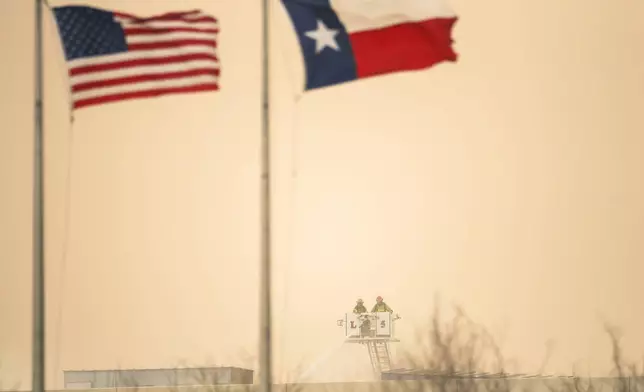 As a dust storm hits the area, firefighters spray water on a fire at the maintenance facilities of the public transportation service Sun Metro on Tuesday, Feb. 11, 2025, in El Paso, Texas. (AP Photo/Andres Leighton)