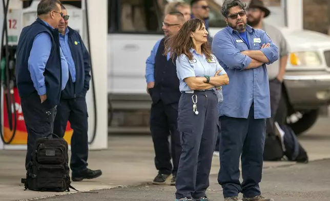 Employees of the public transportation service Sun Metro wait at a gas station after being evacuated from their operations center on Tuesday, Feb. 11, 2025, in El Paso, Texas. (AP Photo/Andres Leighton)