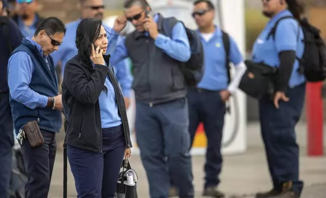Employees of the public transportation service Sun Metro wait at a gas station after being evacuated from their operations center due to a fire Tuesday, Feb. 11, 2025, in El Paso, Texas. (AP Photo/Andres Leighton)