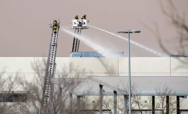 Firefighters spray water on the maintenance facilities of the public transportation service Sun Metro on Tuesday, Feb. 11, 2025, in El Paso, Texas. (AP Photo/Andres Leighton)