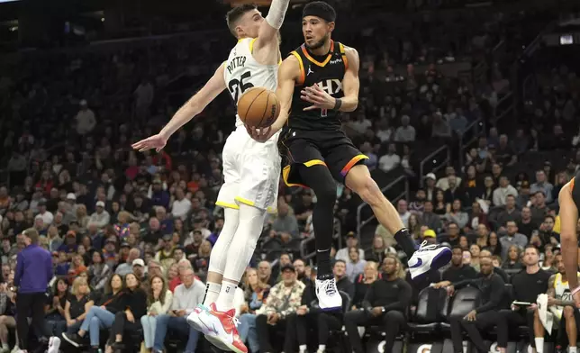 Phoenix Suns guard Devin Booker (1) makes the pass around Utah Jazz center Micah Potter during the first half of an NBA basketball game, Friday, Feb. 7, 2025, in Phoenix. (AP Photo/Rick Scuteri)