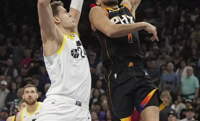 Phoenix Suns guard Devin Booker (1) shoots in front of Utah Jazz center Walker Kessler during the first half of an NBA basketball game, Friday, Feb. 7, 2025, in Phoenix. (AP Photo/Rick Scuteri)