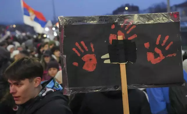 A man holds a banner with red hands symbolizing blood during a student-led large protest and a 15-hour blockade of the streets in Serbian industrial town of Kragujevac, to protest the deaths of 15 people killed in the November collapse of a train station canopy, Saturday, Feb. 15, 2025. (AP Photo/Darko Vojinovic)
