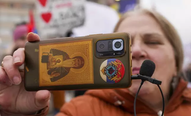 A woman records video with her smartphone during a protest triggered after a concrete canopy on a railway station in the northern city of Novi Sad collapsed on Nov. 1, 2024 killed 15 people, in Kragujevac, Serbia, Saturday, Feb. 15, 2025. (AP Photo/Darko Vojinovic)