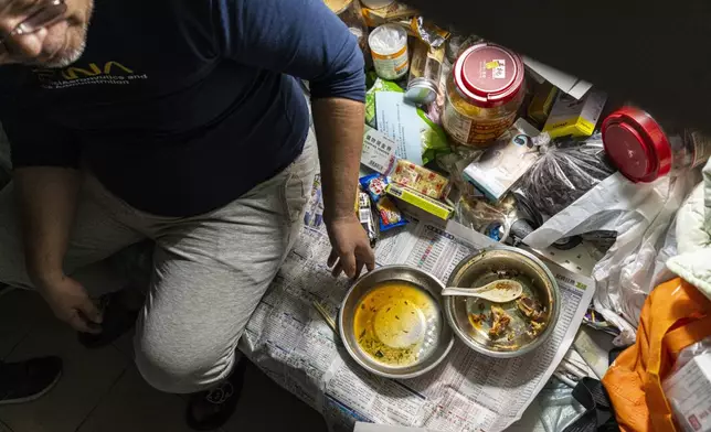 Resident Law Chung-yu has dinner in his bed space in Sham Shui Po district of Hong Kong, on Feb. 6, 2025. (AP Photo/Chan Long Hei)